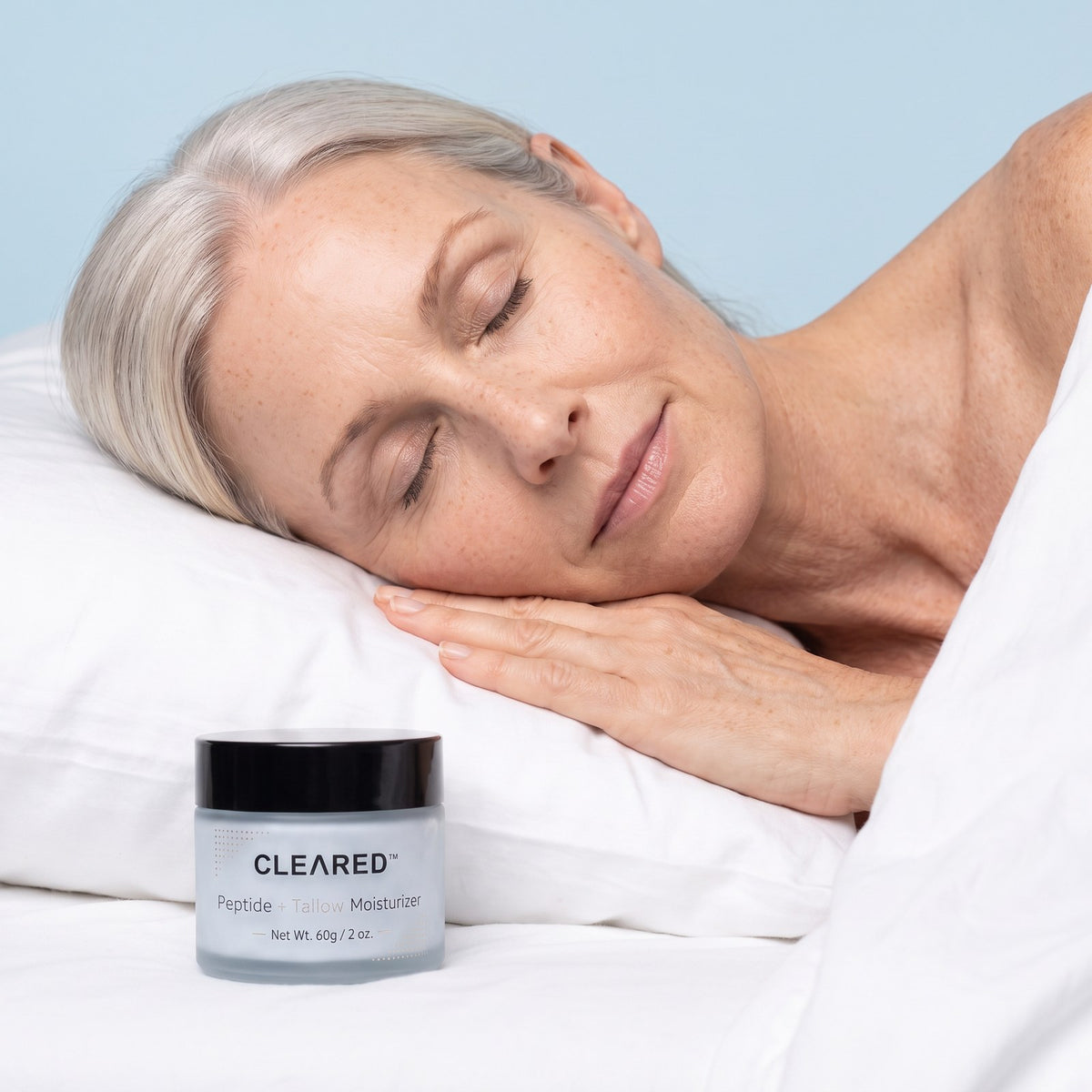 A woman asleep on a white pillow with a jar of CLEARED beside her