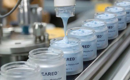 Jars being filled with the pale-blue whipped balm
